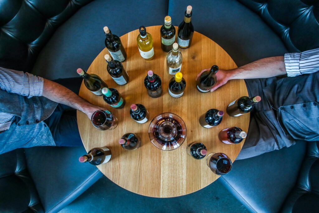 person holding glass bottle on round brown wooden table Same-Day Wine Delivery in Zürich & Zug